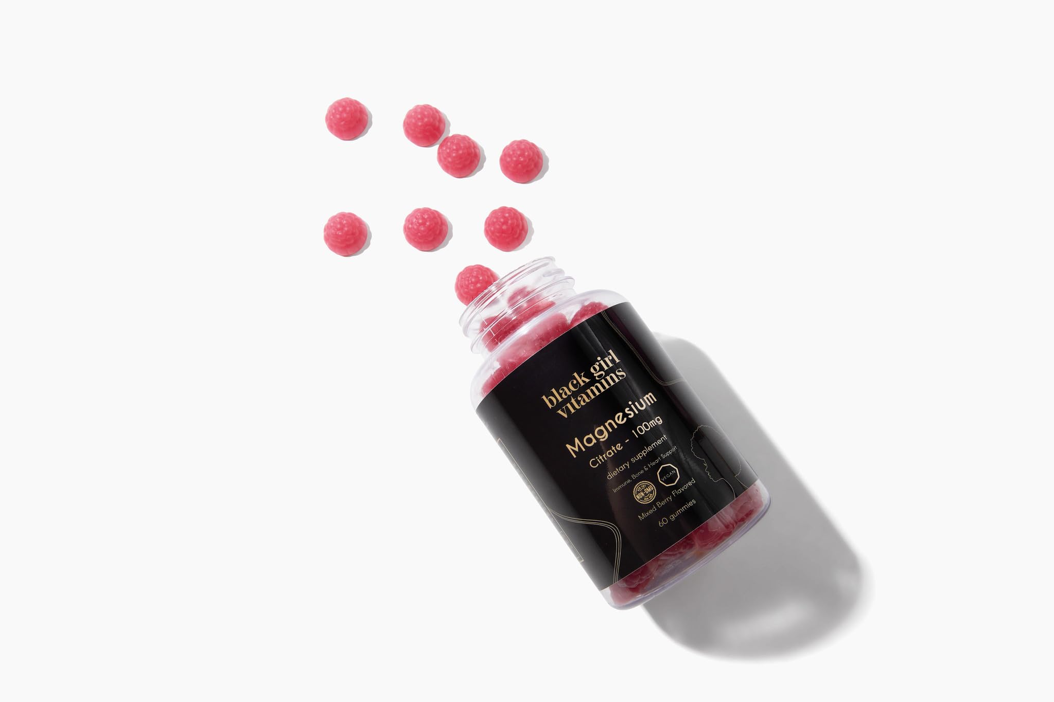 Black Girl Vitamins frasco junto a frutas mixed berry para contexto de sabor