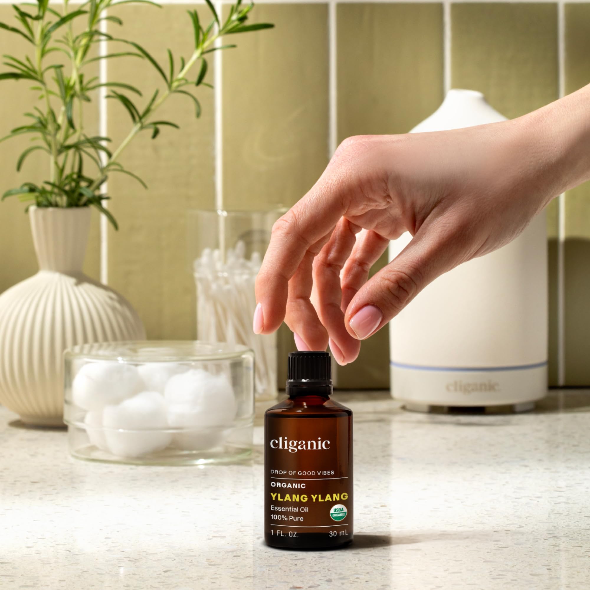 Cliganic frasco de Ylang Ylang comparado con mano para escala de tamaño