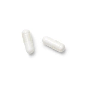 persona tomando cápsula GNC L-Glutamine junto a botella de agua tras entreno para apoyar recuperación