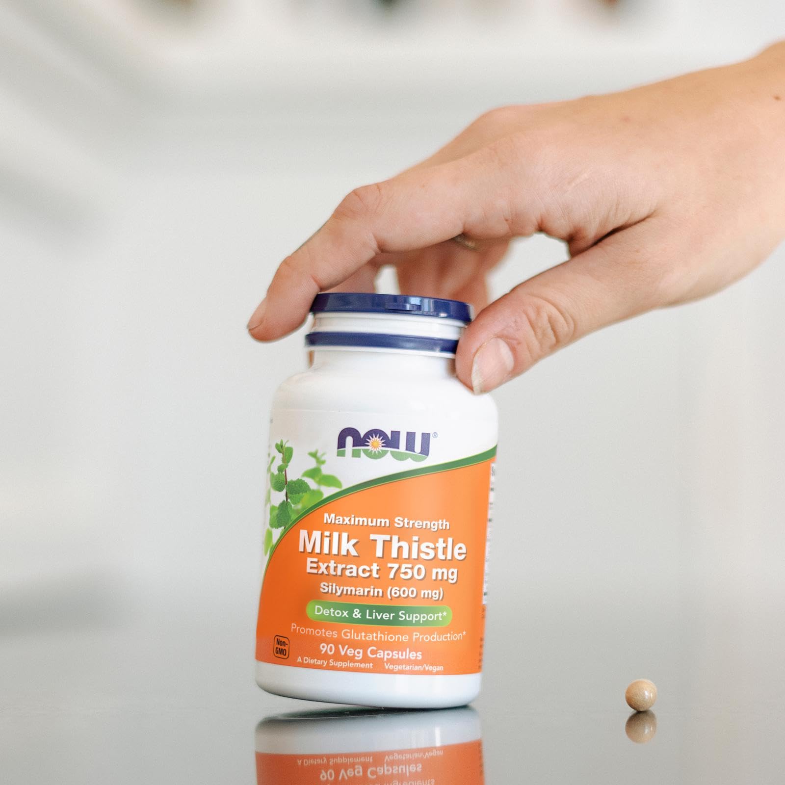 NOW Foods comparación de tamaño de la cápsula con una moneda para escala