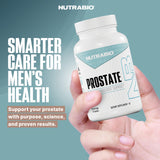 NutraBio Prostate cápsula junto a moneda para comparar tamaño