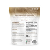 OM MUSHROOM SUPERFOOD pouch junto a fruta para referencia de tamaño