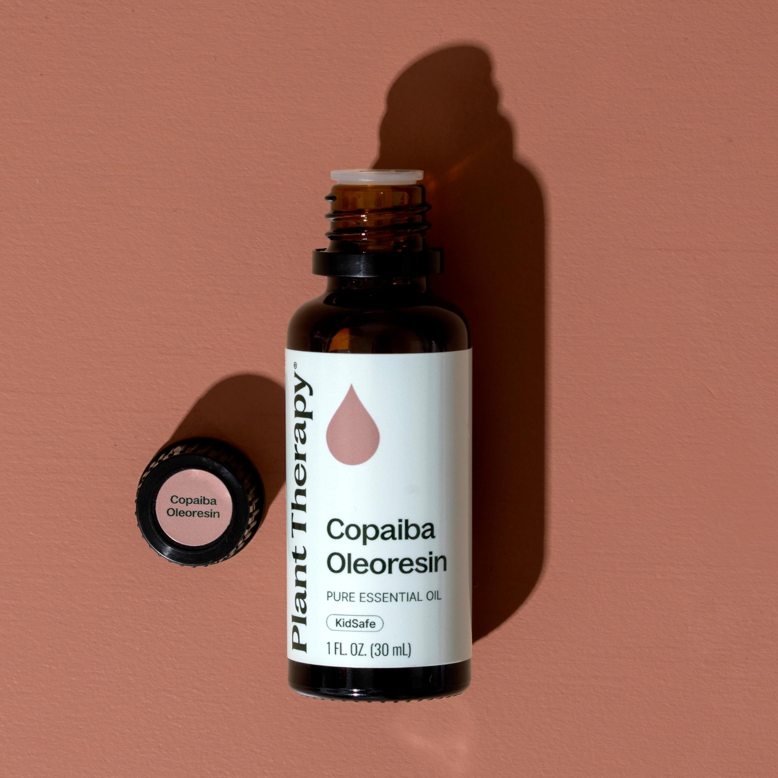 Plant Therapy frasco de Copaiba junto a moneda para comparar tamaño real