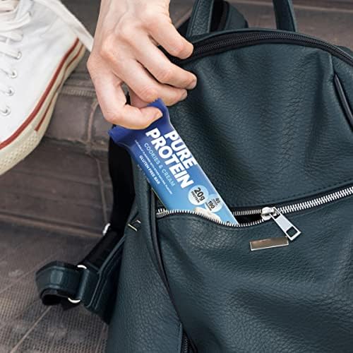 Pure Protein barra en mano en gimnasio, snack proteico práctico